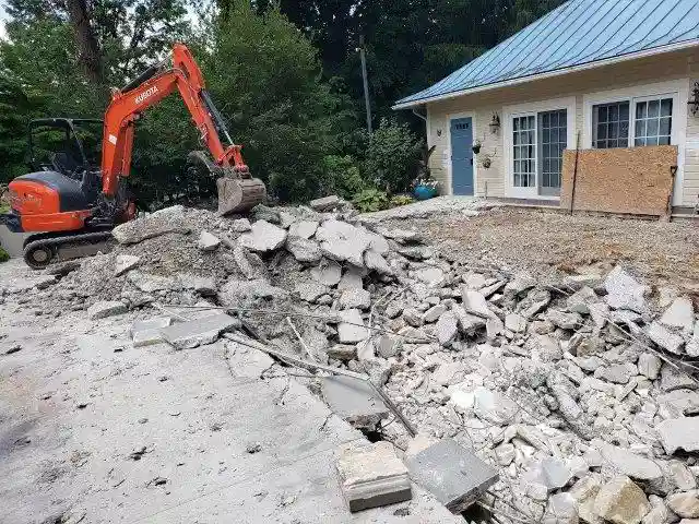 A Maryland backyard during pool demolition by Remove A Pool, with heavy machinery breaking up the concrete and debris scattered around.