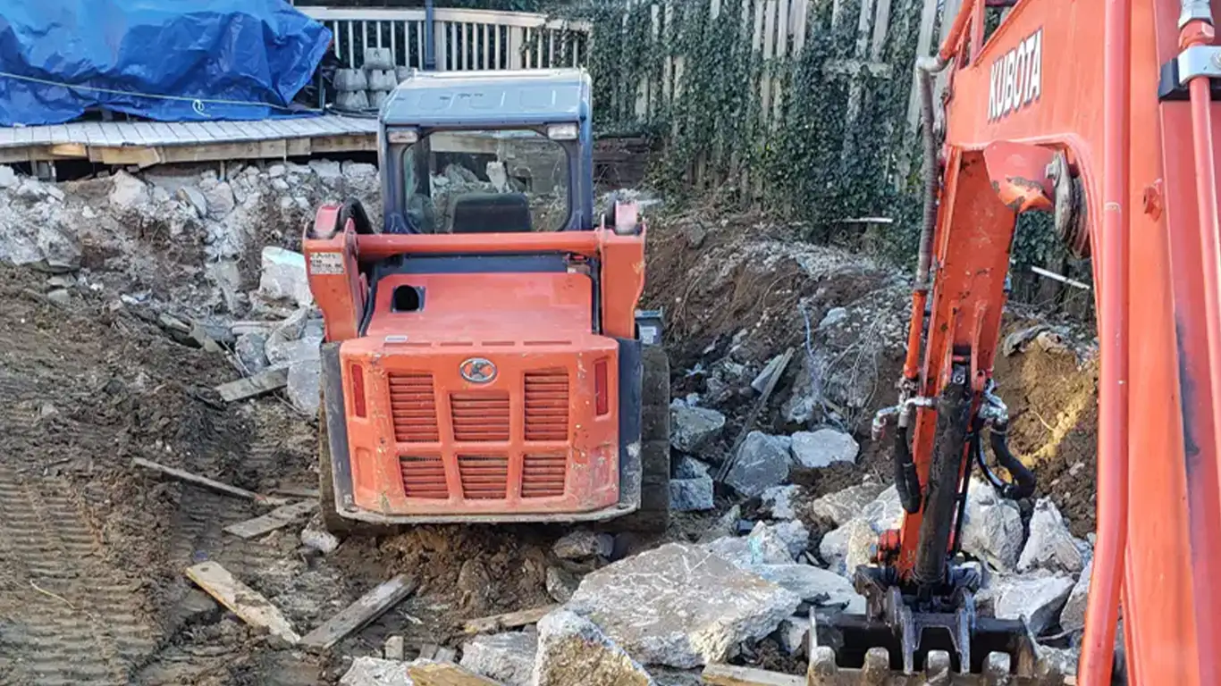 A Kubota excavator and a loader work together in the middle of a pool demolition project. Pool Removal Pennsylvania by Remove A Pool.