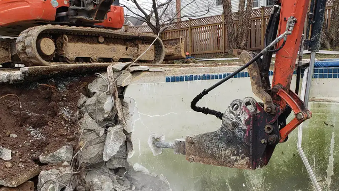 Excavator demolishing an inground pool in Texas, breaking concrete walls during removal. Remove A Pool offers expert pool demolition services locally.