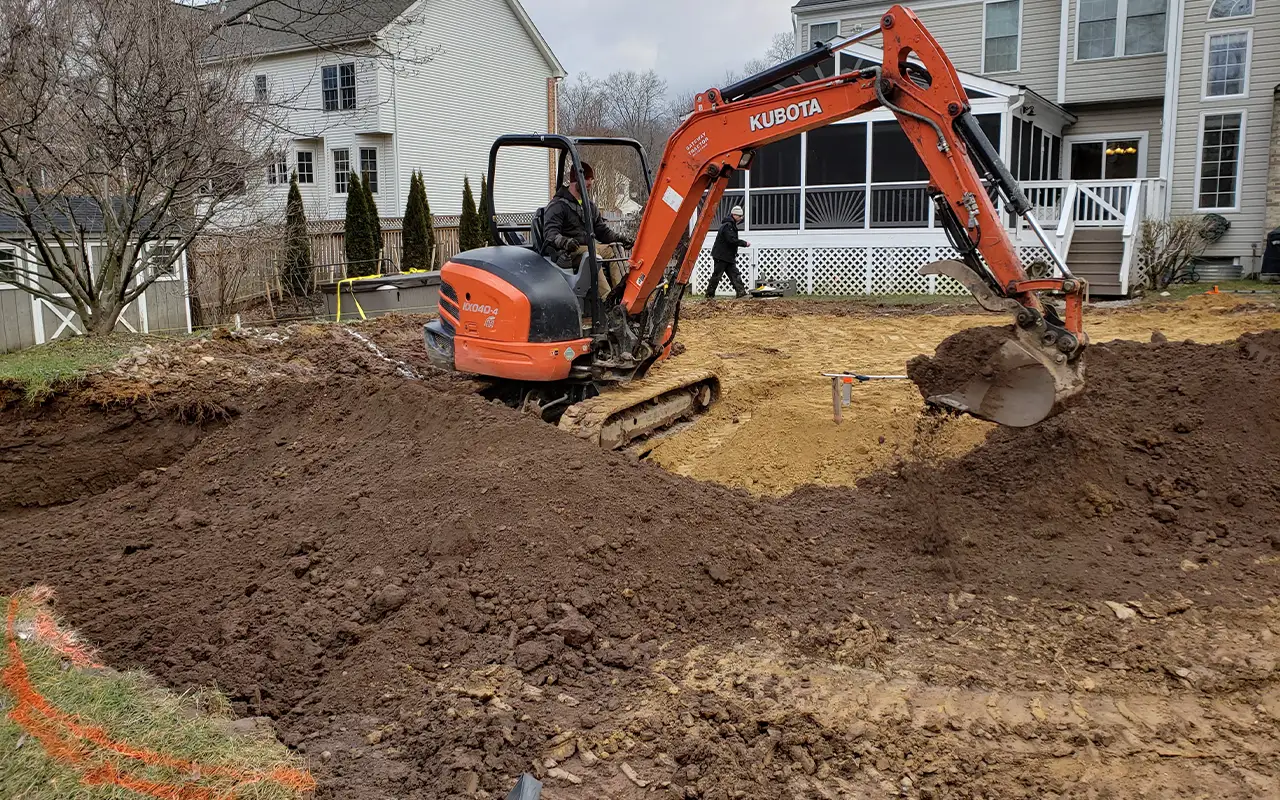 An excavator from Remove A Pool conducting a pool filling project in Annandale, Virginia, as part of the process of restoring a residential backyard.