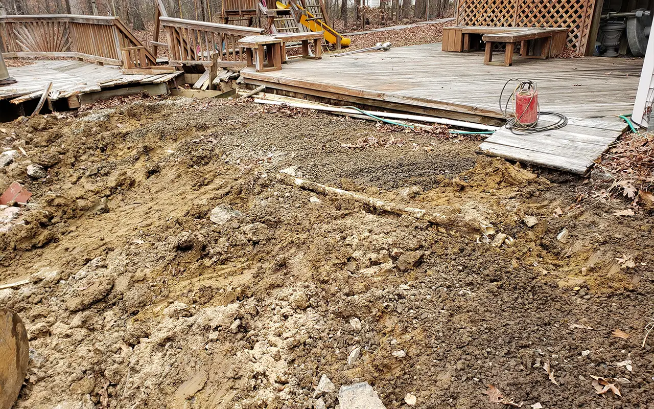 A backyard in Arlington TX undergoing pool filling, where Remove A Pool has leveled the ground after removing an old swimming pool next to a wooden deck.