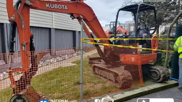 A Kubota excavator is placed behind safety fencing, set up for a pool removal project near a building.