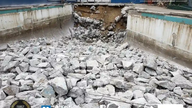 Broken concrete debris covering the bottom of a drained pool as the excavation continues.