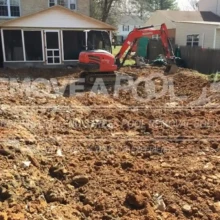Compacting and grading the soil ensures a stable surface following the pool removal process. Heavy equipment compacting soil at the pool site.
