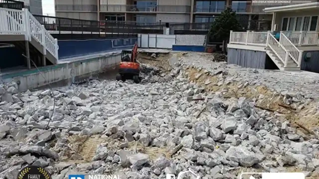 A cleared pool site with deep excavation underway and large concrete chunks spread across the area.